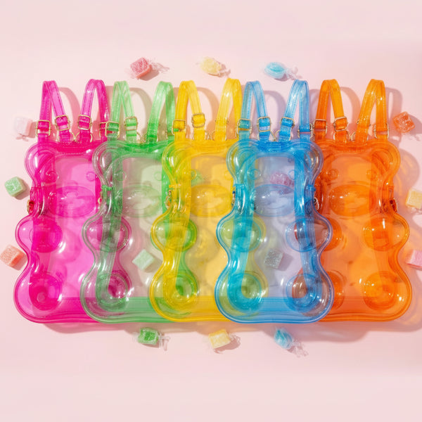 Top-down view of five transparent glitter bear-shaped backpacks in bright rainbow colors