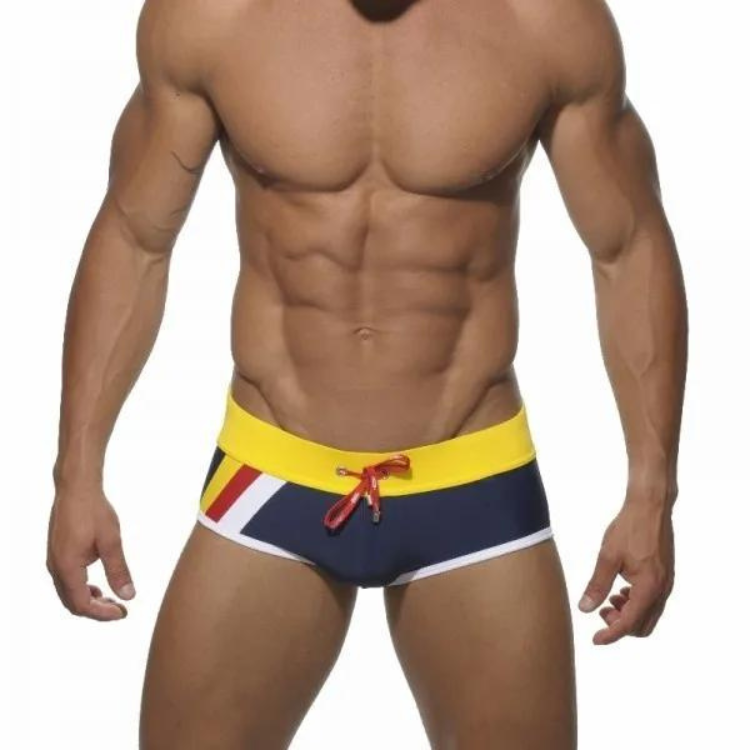 Front view of a model wearing navy square-cut swim briefs with yellow waistband and stripes