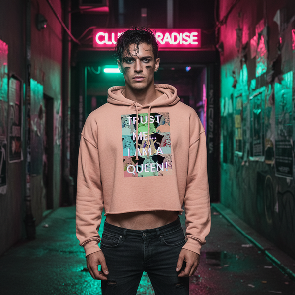 Trust Me...I Am A Queen! Crop Hoodie in bold print, worn by a person with dramatic makeup in a neon-lit, pride-filled alley