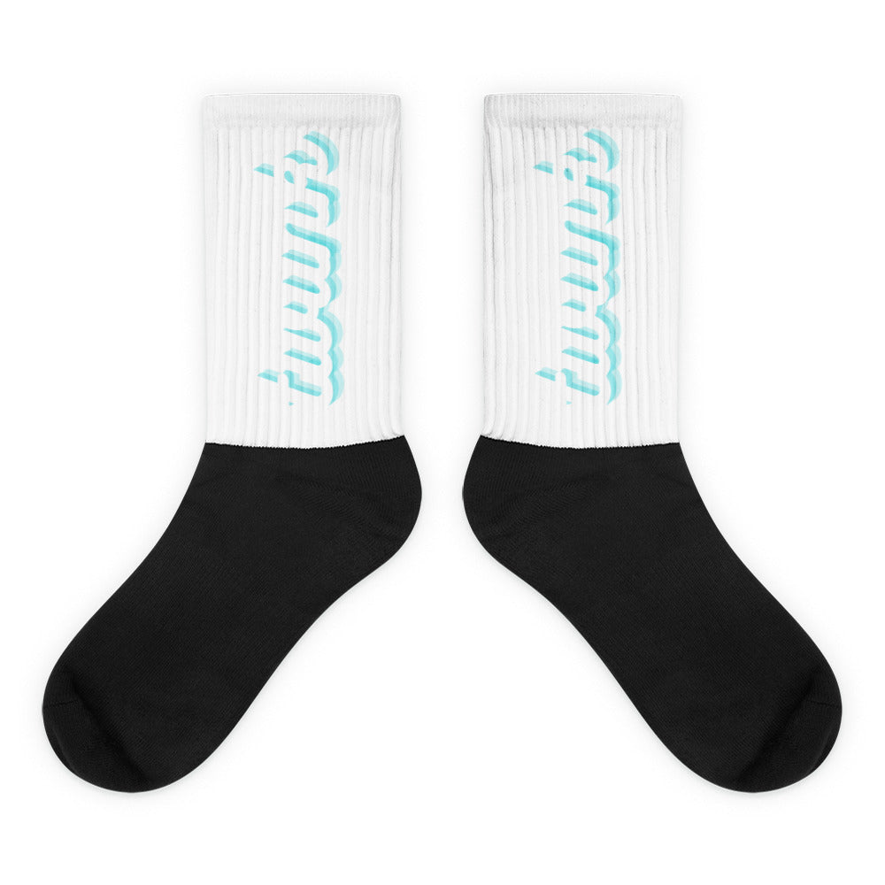 Pair of crew socks with white ribbed cuffs, turquoise lettering, and black feet