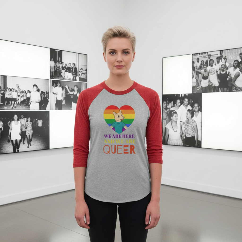 Front-facing model wearing a gray raglan shirt with red sleeves and a rainbow heart reading “WE ARE HERE AND WE ARE QUEER.”