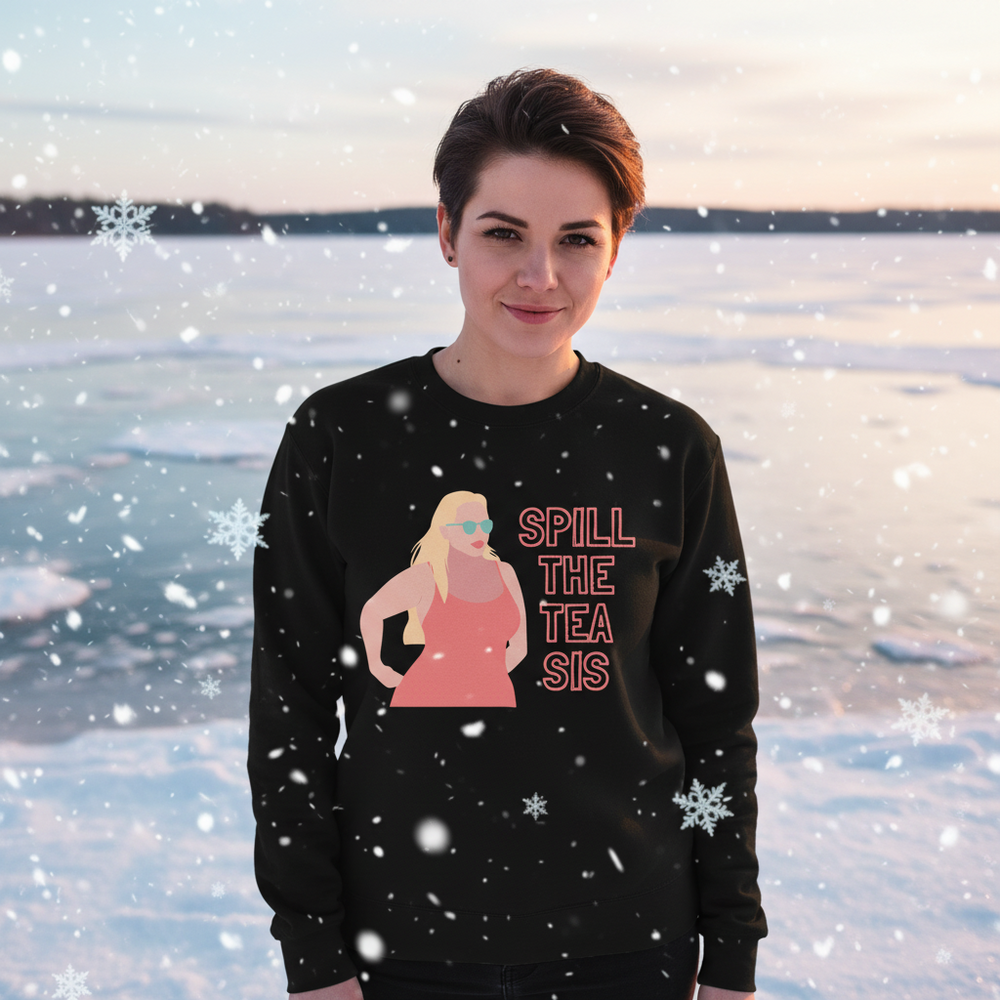 Black sweatshirt with “SPILL THE TEA SIS” graphic, modeled against a snowy lakeside