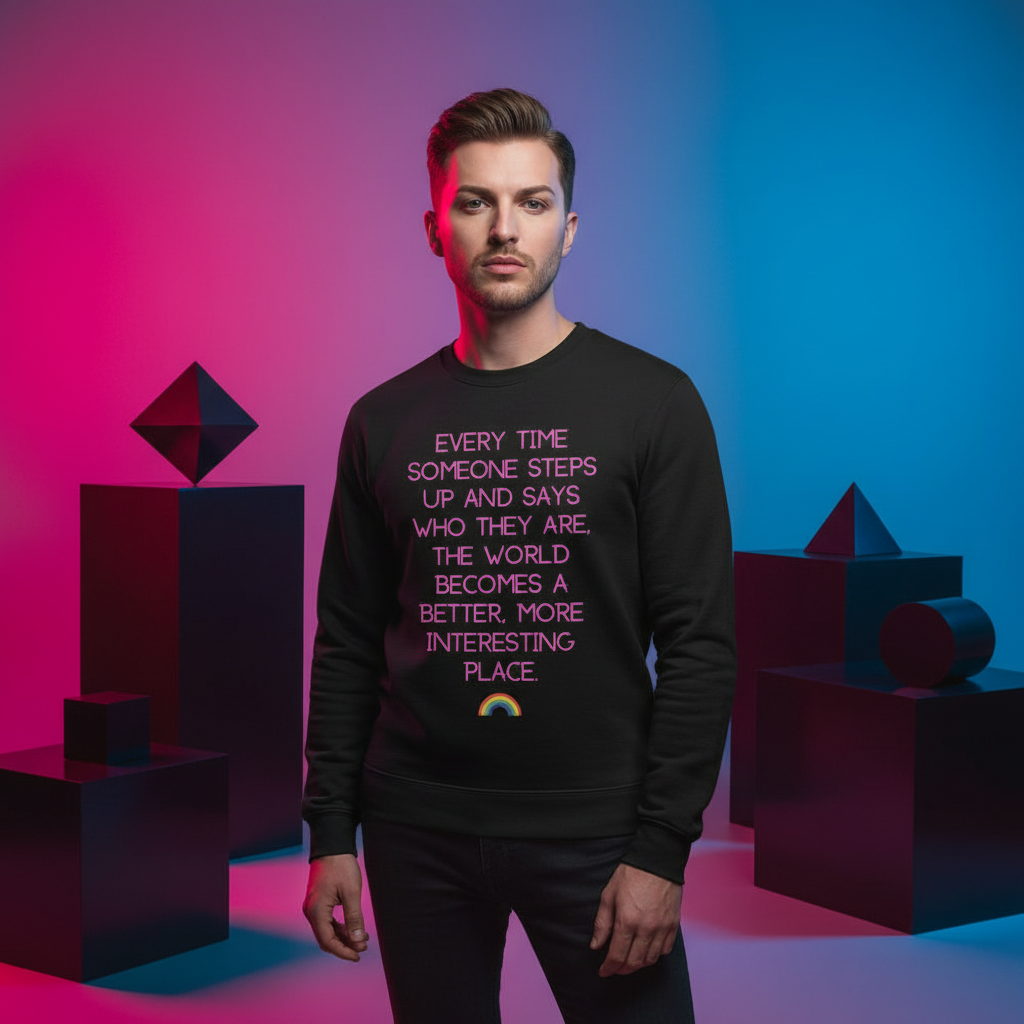 Young male model showcases the Every Time Someone Steps Up Unisex Sweatshirt, featuring an empowering message and rainbow graphic, expressing queer pride and self-expression in a modern, artistic studio setting.