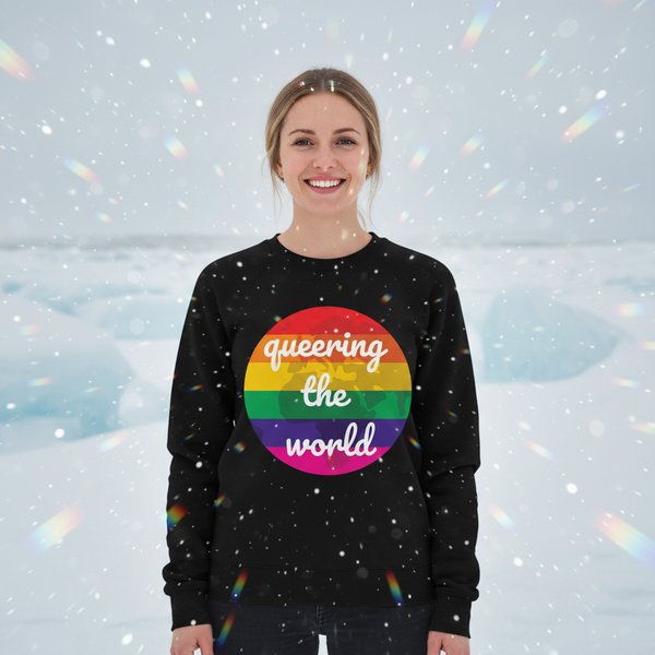 Person wearing a black sweatshirt with a rainbow-striped “queering the world” graphic
