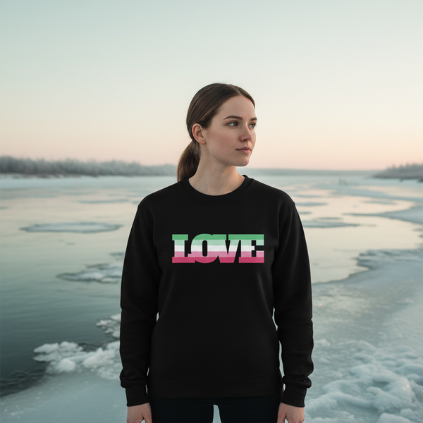 Person wearing a black sweatshirt with striped “LOVE” lettering beside a frozen lake