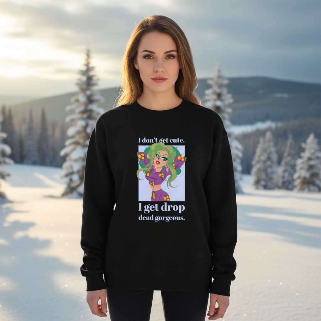 Young woman stands in snowy landscape wearing the Drop Dead Gorgeous Unisex Sweatshirt, featuring a vibrant cartoon design and empowering message. The sweatshirt embodies pride and self-expression with cozy comfort and queer flair.
