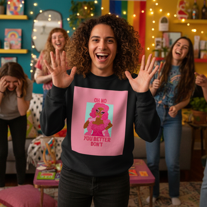 Curly-haired person in an Oh No You Betta Don't Unisex Sweatshirt, smiling joyfully in a colorful, prideful living room, embodying empowerment and self-expression amidst a lively gathering.