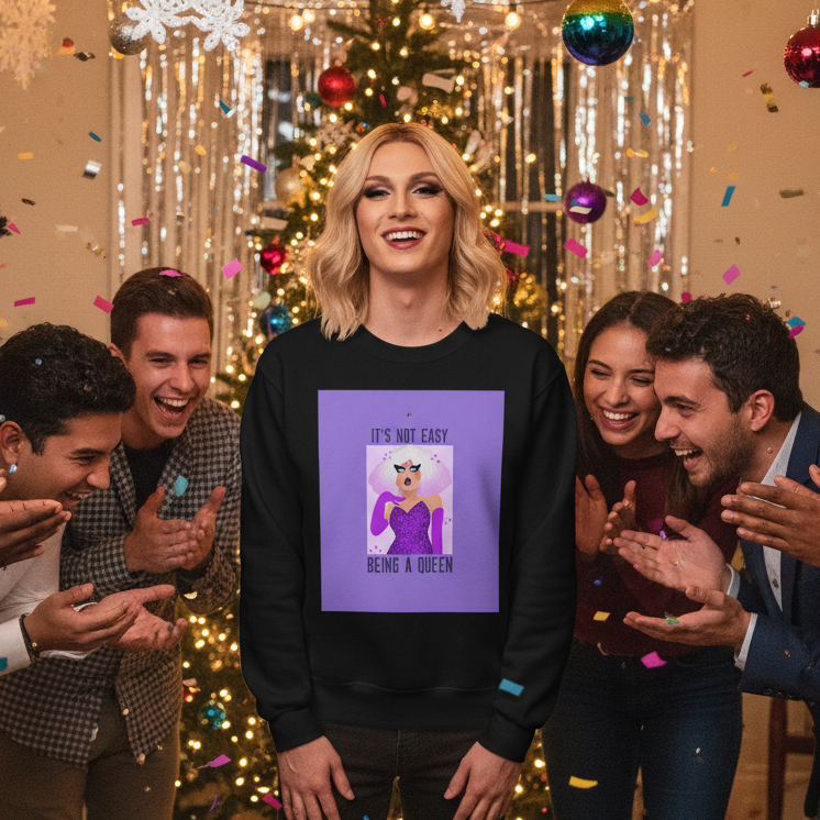 Person in drag wearing the It's Not Easy Being a Queen unisex sweatshirt, celebrating with confetti among friends. Christmas tree and decorations enhance the joyous, prideful atmosphere.