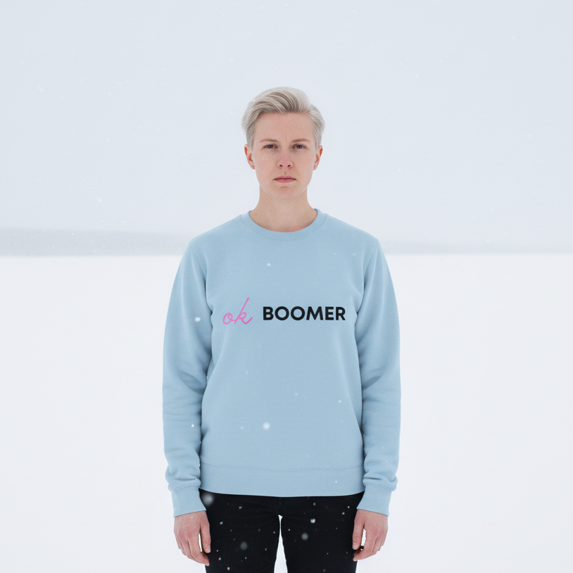 Front-facing person in falling snow wearing a light-blue sweatshirt reading “ok BOOMER”