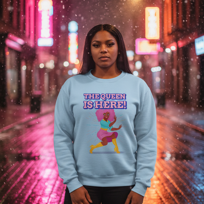Front view of a person wearing a light blue sweatshirt reading “THE QUEEN IS HERE!”