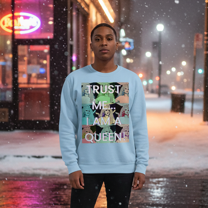 A young person models the Trust Me... I Am A Queen! Unisex Sweatshirt, featuring pop-art dog faces and bold text, blending warmth and pride in a snowy, urban setting, celebrating LGBTQ visibility.