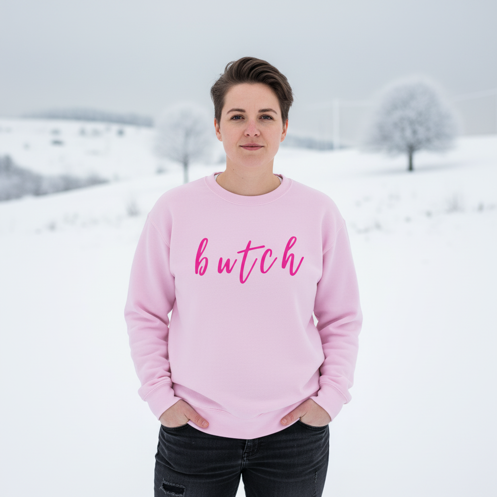 Front-facing model in a pink sweatshirt reading “butch” against a snowy landscape