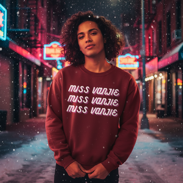Model wearing a burgundy sweatshirt with repeated “MISS VANJIE” lettering in a snowy neon-lit street