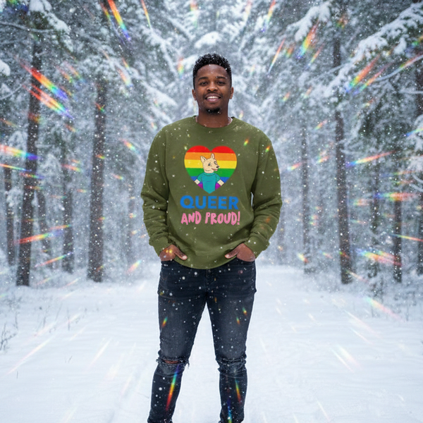 Person wearing an olive sweatshirt with a rainbow heart, fox, and “QUEER AND PROUD!” text in a snowy forest