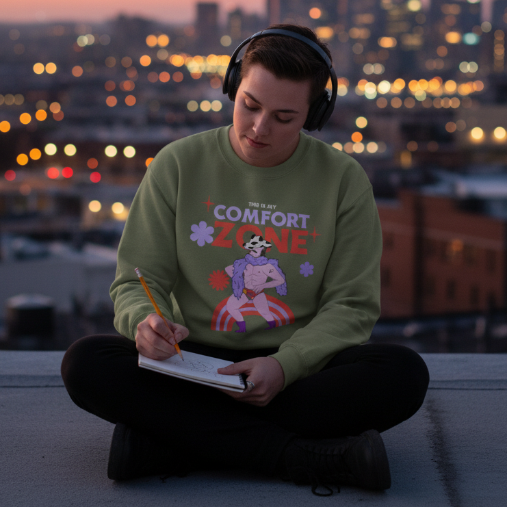 Person wearing the This Is My Comfort Zone Unisex Sweatshirt sits cross-legged on a rooftop, sketching. The sweatshirt features a playful, feather-boa-clad skeleton design, embodying queer pride and self-expression.