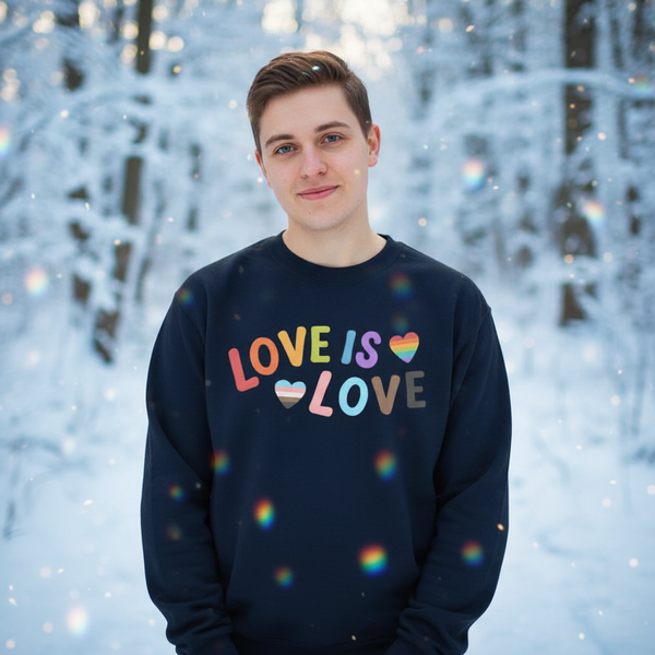 Person wearing a navy sweatshirt reading “LOVE IS LOVE” with rainbow hearts in a snowy forest