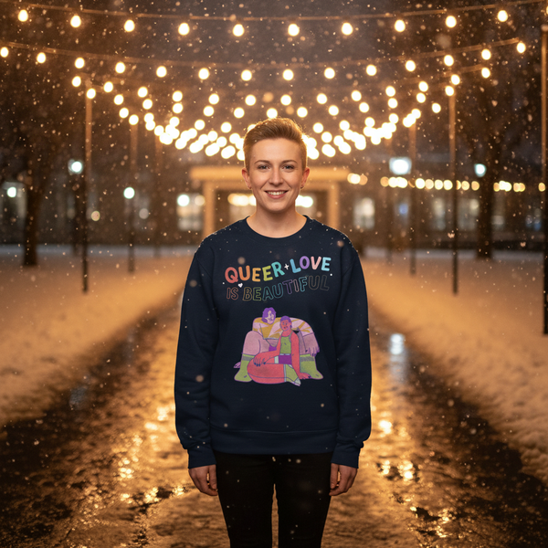 Person wearing a navy sweatshirt reading “QUEER LOVE IS BEAUTIFUL” in falling snow