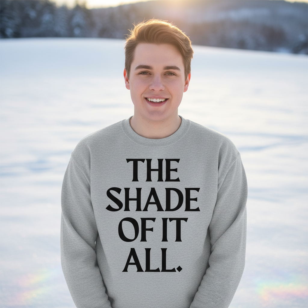 Young man smiling in a snowy landscape, wearing The Shade Of It All Unisex Sweatshirt from Queer In The World, celebrating LGBTQ pride with bold lettering and cozy warmth for self-expression.