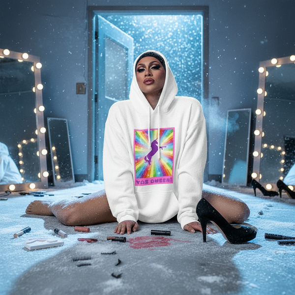 Person kneeling in a white hoodie with a rainbow unicorn graphic and “YAS QWEEN!” text