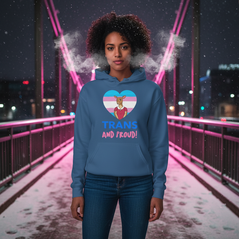 Model wearing a blue hoodie with a transgender-flag heart and “TRANS AND PROUD!” text on a snowy bridge