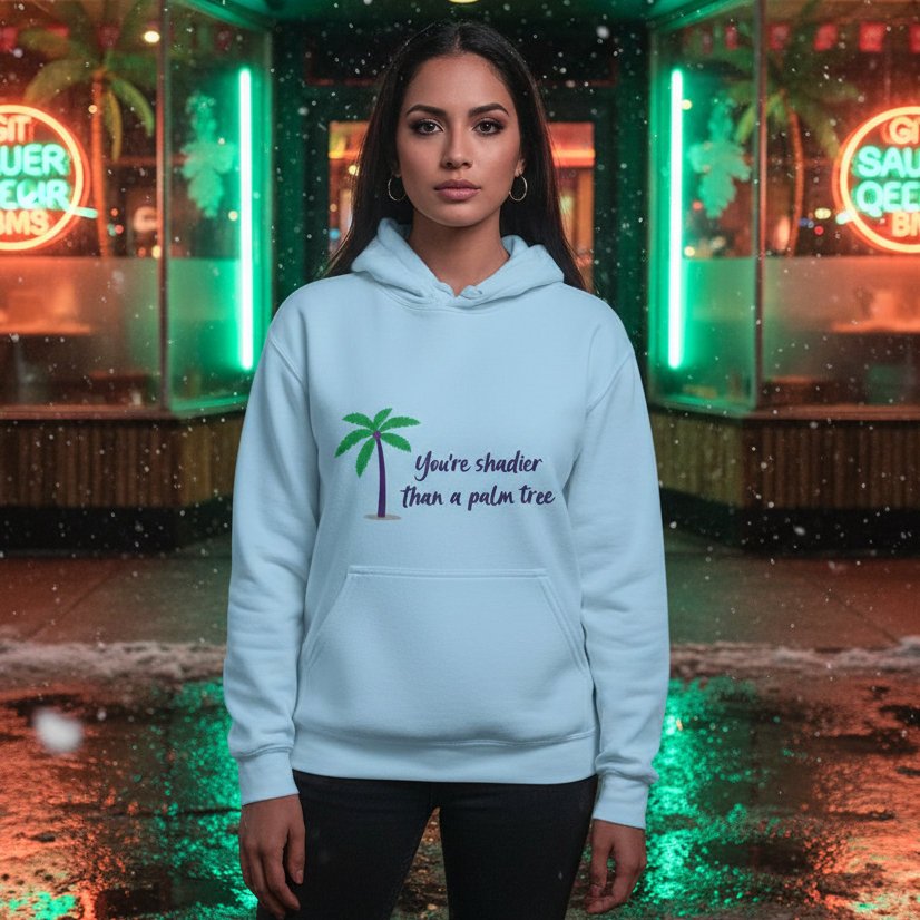 Young woman in a Shadier Than A Palm Tree Unisex Hoodie, standing amid neon-lit reflections. The hoodie embodies cozy, playful self-expression, celebrating queer pride and visibility with a chic, inclusive design.