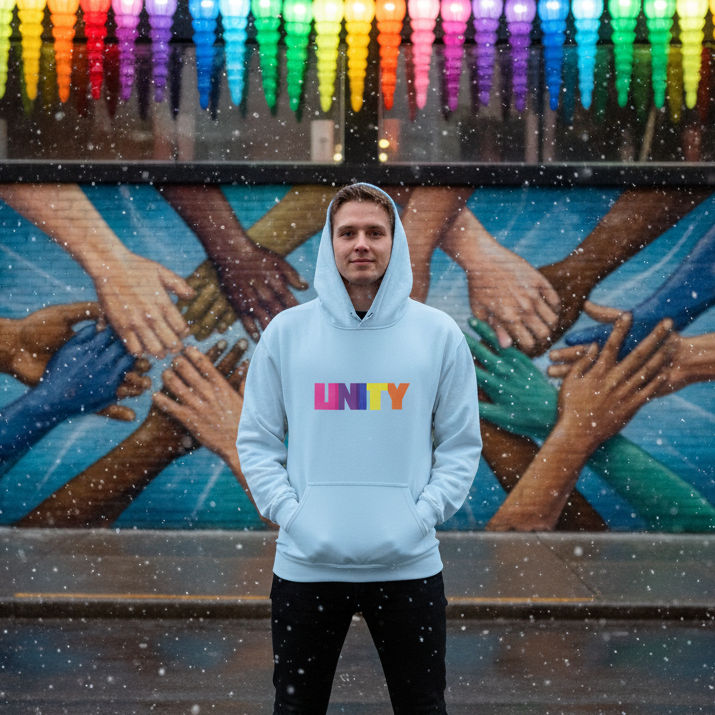 A young person models the Unity Unisex Hoodie, featuring UNITY in bold, multicolored letters, epitomizing pride and inclusivity, standing before a mural of diverse hands symbolizing community and connection.
