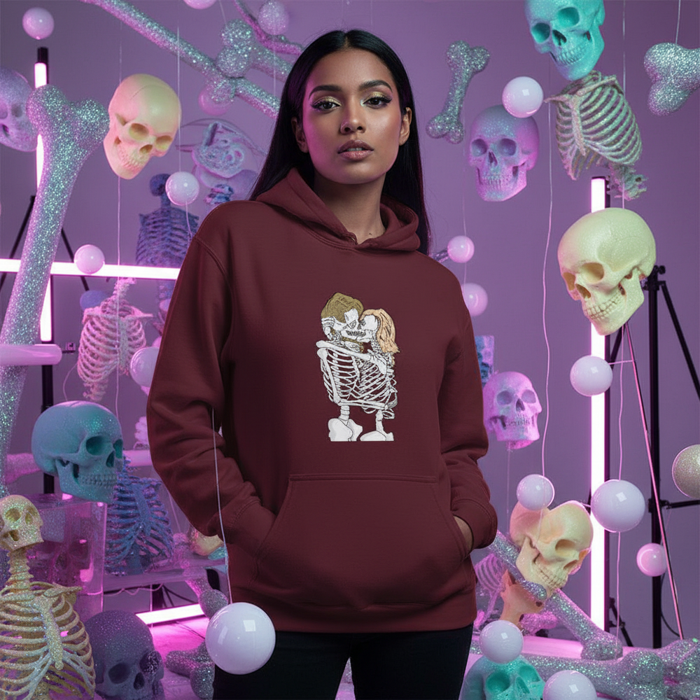 Model wearing a burgundy hoodie with an embracing skeleton couple graphic amid colorful skeleton props