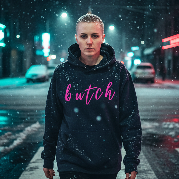 Person wearing a black hoodie with pink “butch” lettering in a snowy city street