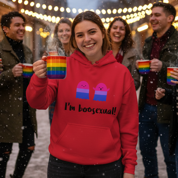 Smiling person in a red “I’m boosexual!” hoodie holds a rainbow mug in falling snow