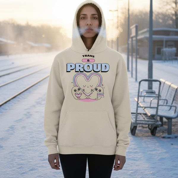 Person in cream “TRANS & PROUD” hoodie on a snowy railway platform