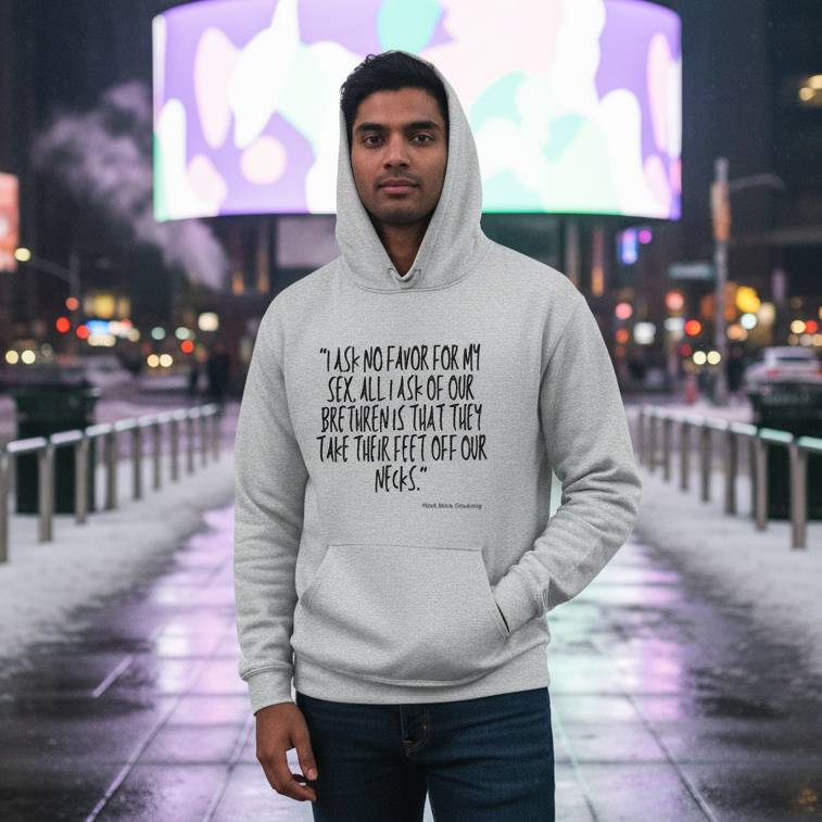 Front-facing person in a gray hoodie with a Sojourner Truth quote, in a snowy city at night