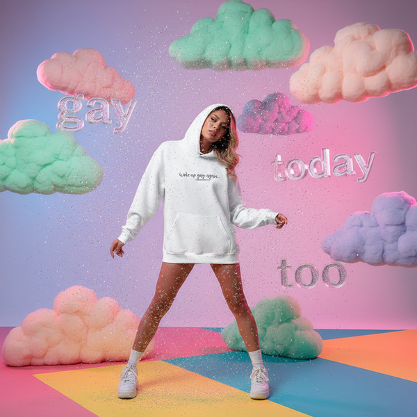 Model wearing a white hoodie reading “Woke up gay again,” among pastel clouds