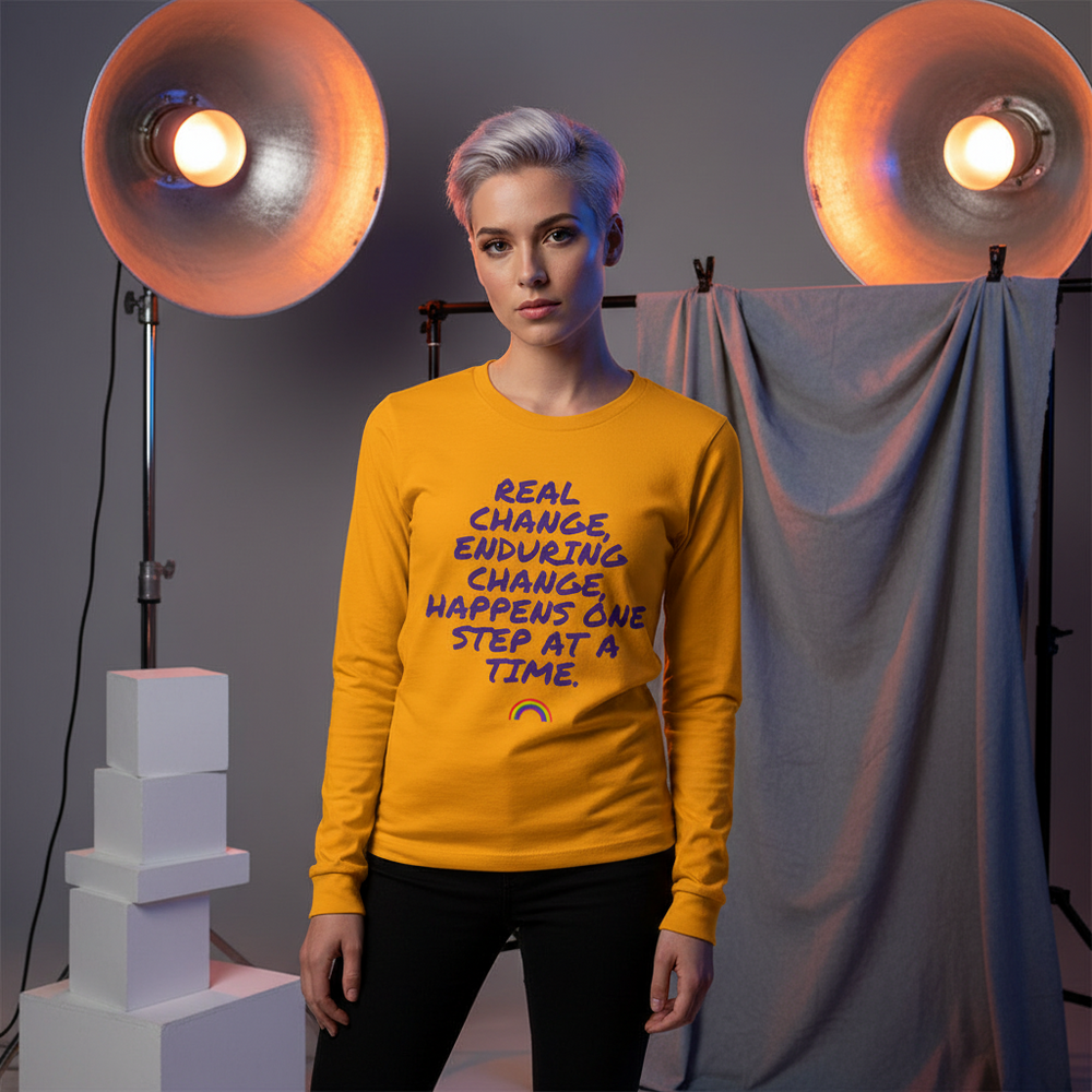 Person modeling a mustard-yellow long-sleeve shirt with purple text and a rainbow icon