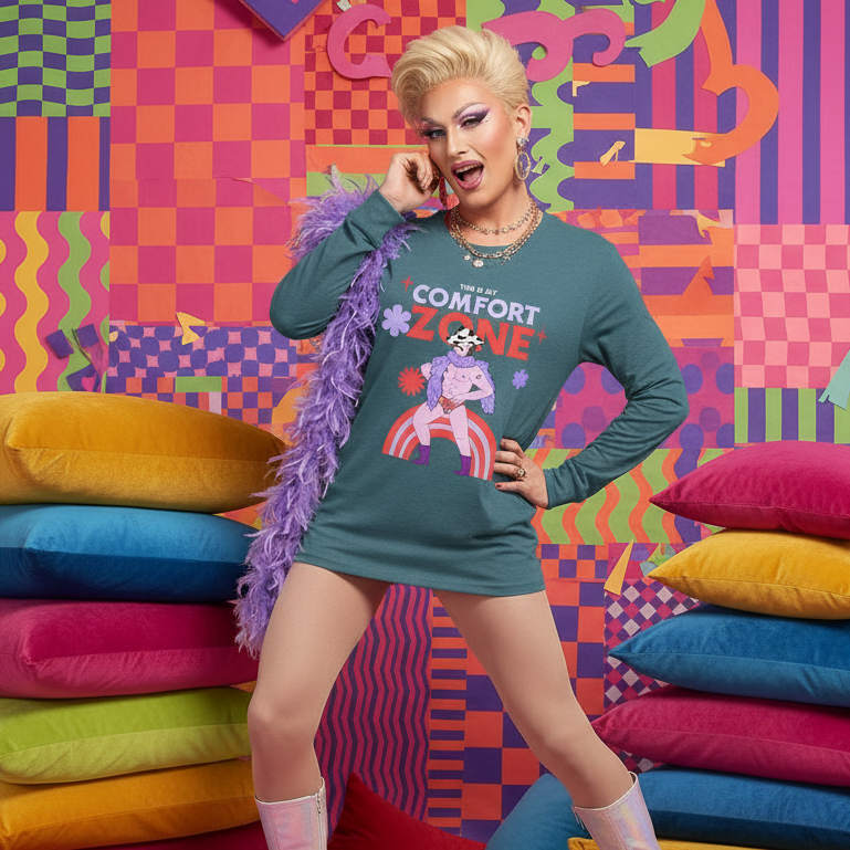 Drag performer wearing the This Is My Comfort Zone Unisex Long Sleeve T-Shirt, teal-green with a retro illustration, paired with a flamboyant ensemble of metallic boots, a feather boa, and chunky jewelry.
