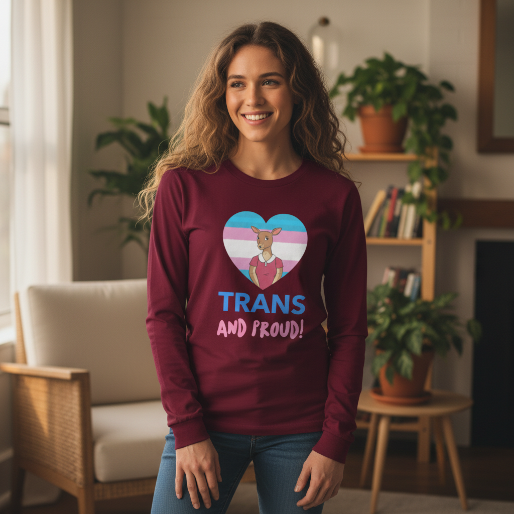 Smiling woman in cozy room wears Trans And Proud Unisex Long Sleeve T-Shirt, featuring a transgender pride heart graphic with a cartoon deer. A vibrant symbol of empowerment and self-expression.