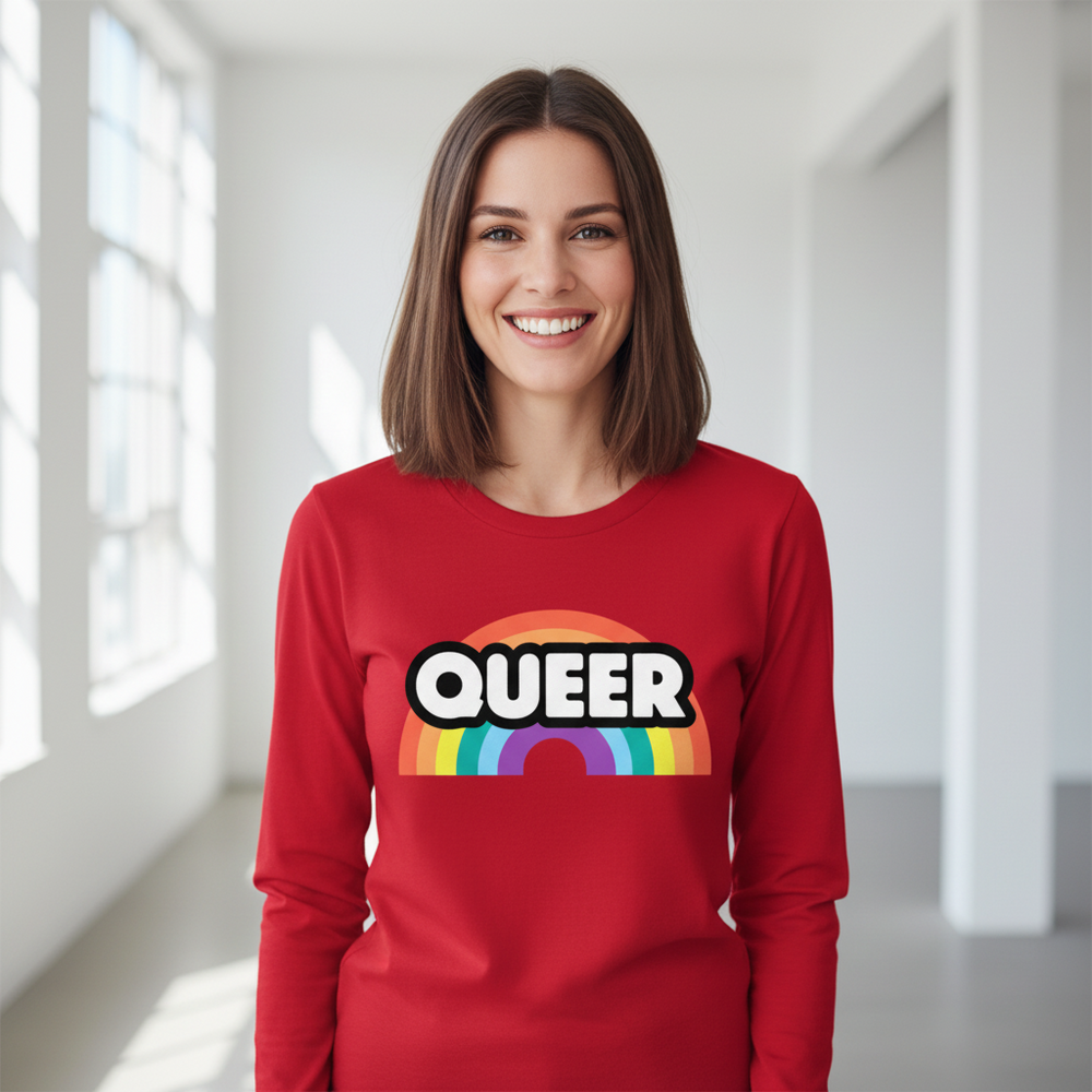 Smiling person wearing a red long-sleeve shirt with “QUEER” over a rainbow graphic