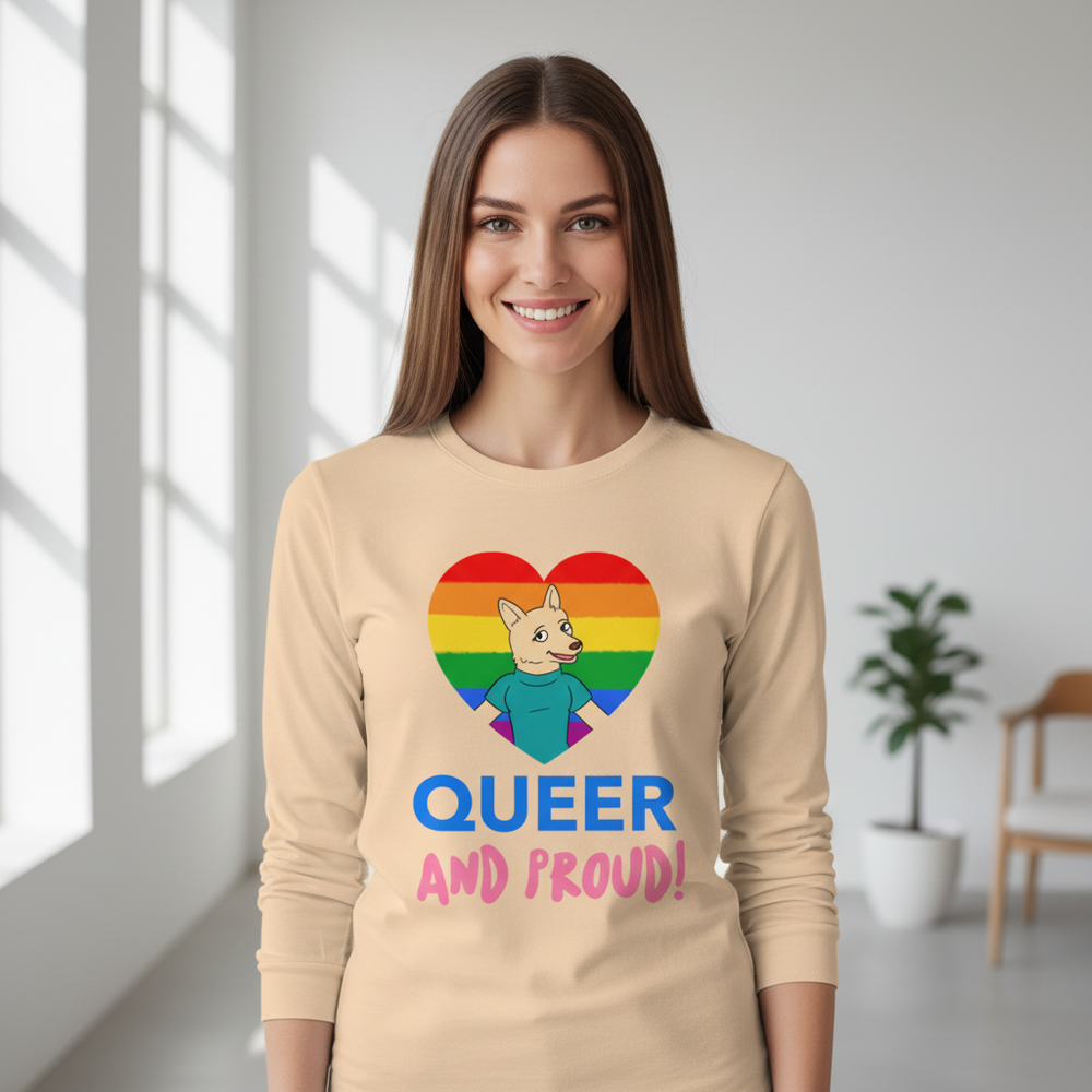 Model wearing a beige long-sleeve shirt with a rainbow heart, cartoon dog, and “QUEER AND PROUD!”