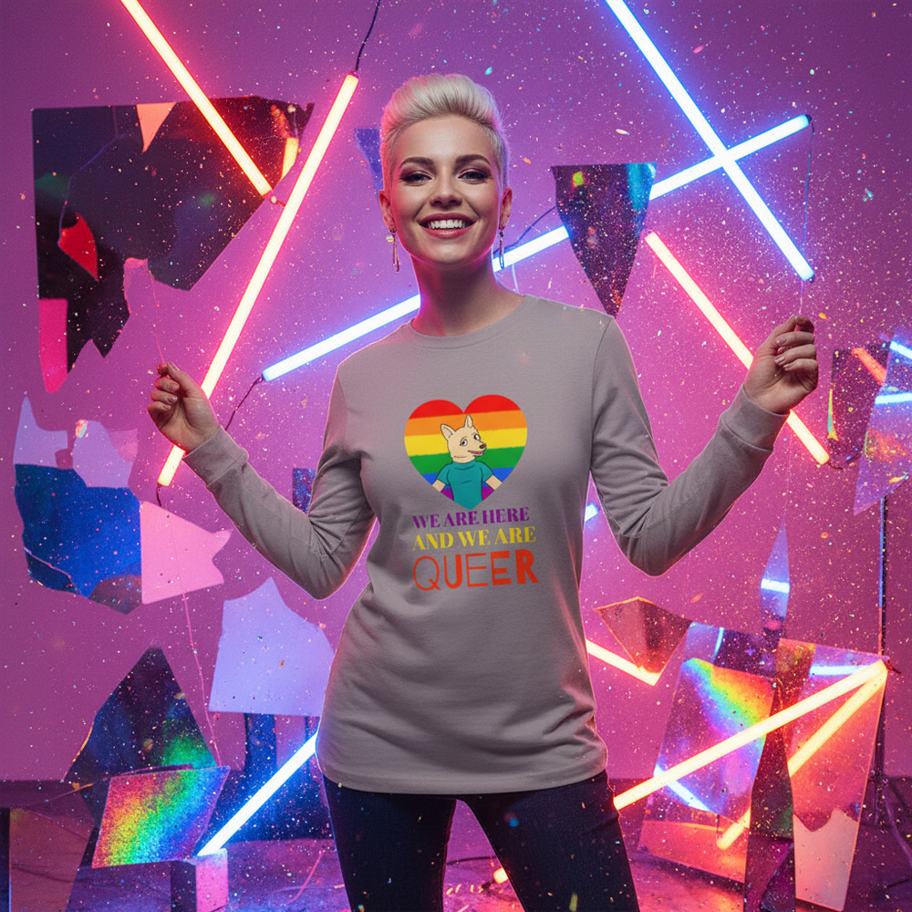 Smiling person models a gray long-sleeve shirt reading “WE ARE HERE AND WE ARE QUEER”