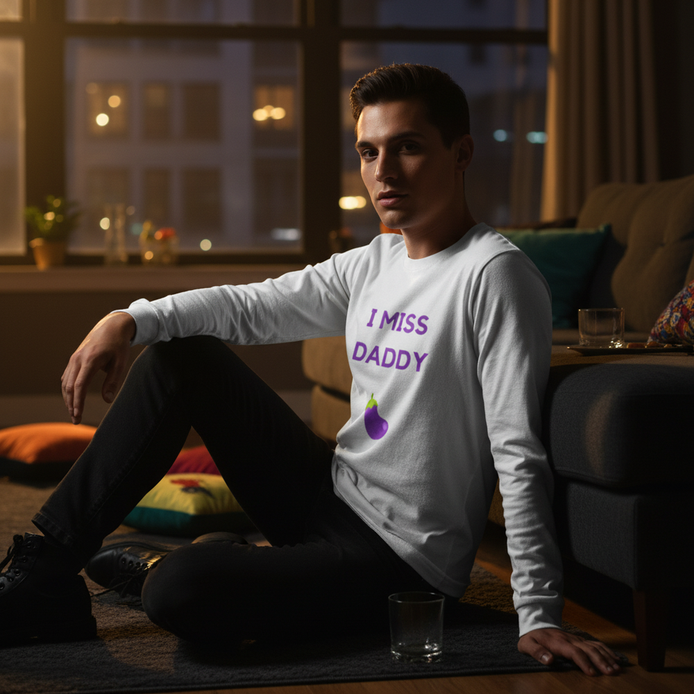 Person seated on a rug wearing a white long-sleeve shirt reading “I MISS DADDY” with an eggplant graphic