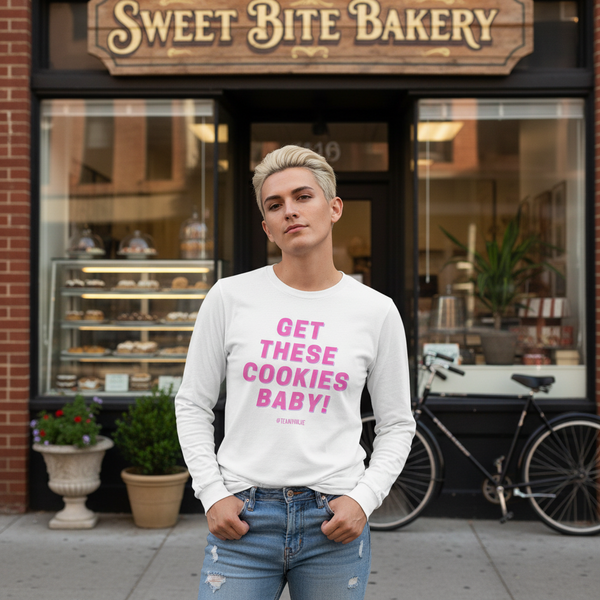 Person modeling a white long-sleeve shirt reading “GET THESE COOKIES BABY!” outside a bakery