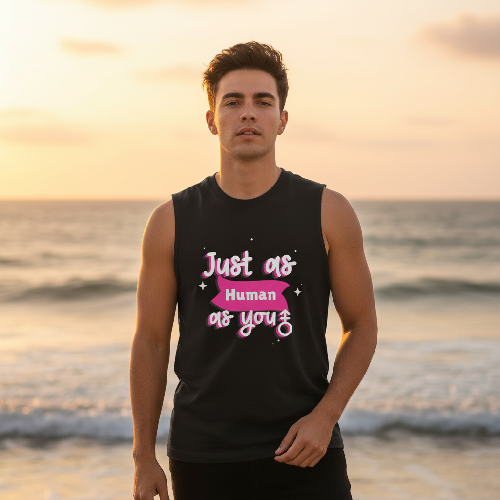 Young man on a beach at sunset wearing the Just As Human As You Muscle Tank, showcasing a bold, empowering slogan in pink-and-white, representing queer pride and self-expression.