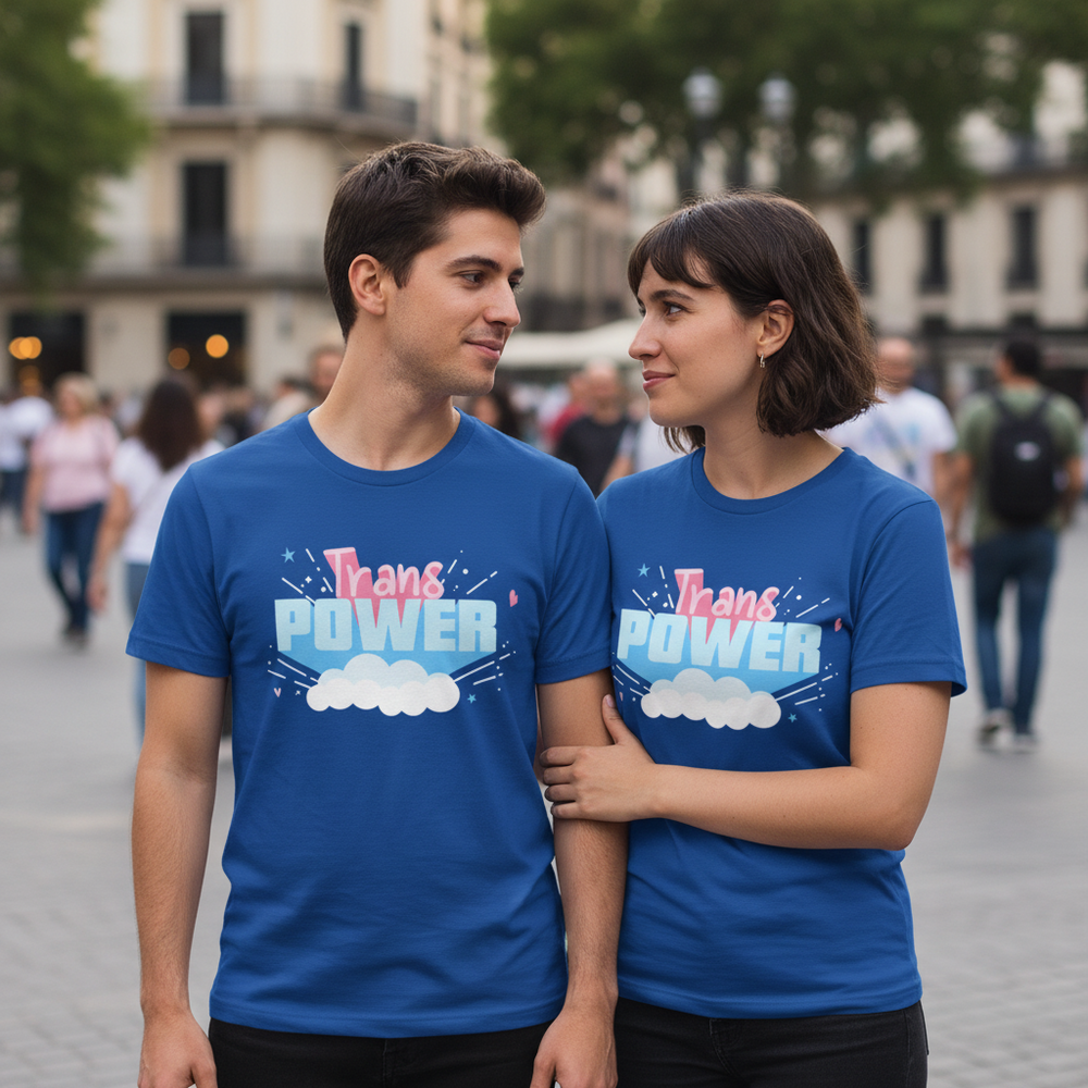 Matching "Trans Power" T-shirts with rainbow accents and a cloud graphic, worn by a queer couple outdoors in an urban crowd.
