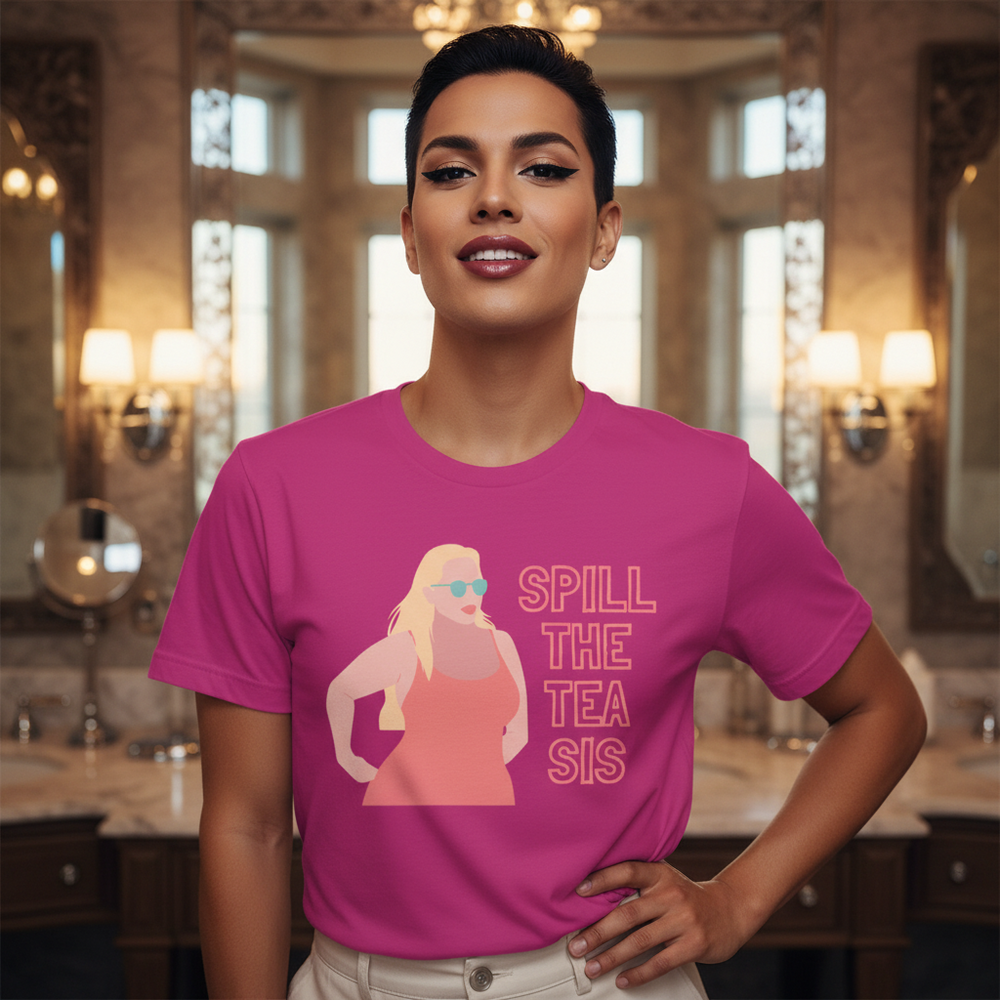 Bright pink unisex Pride T-shirt reads "SPILL THE TEA SIS" with art of a blonde woman in sunglasses; model in luxe bathroom.