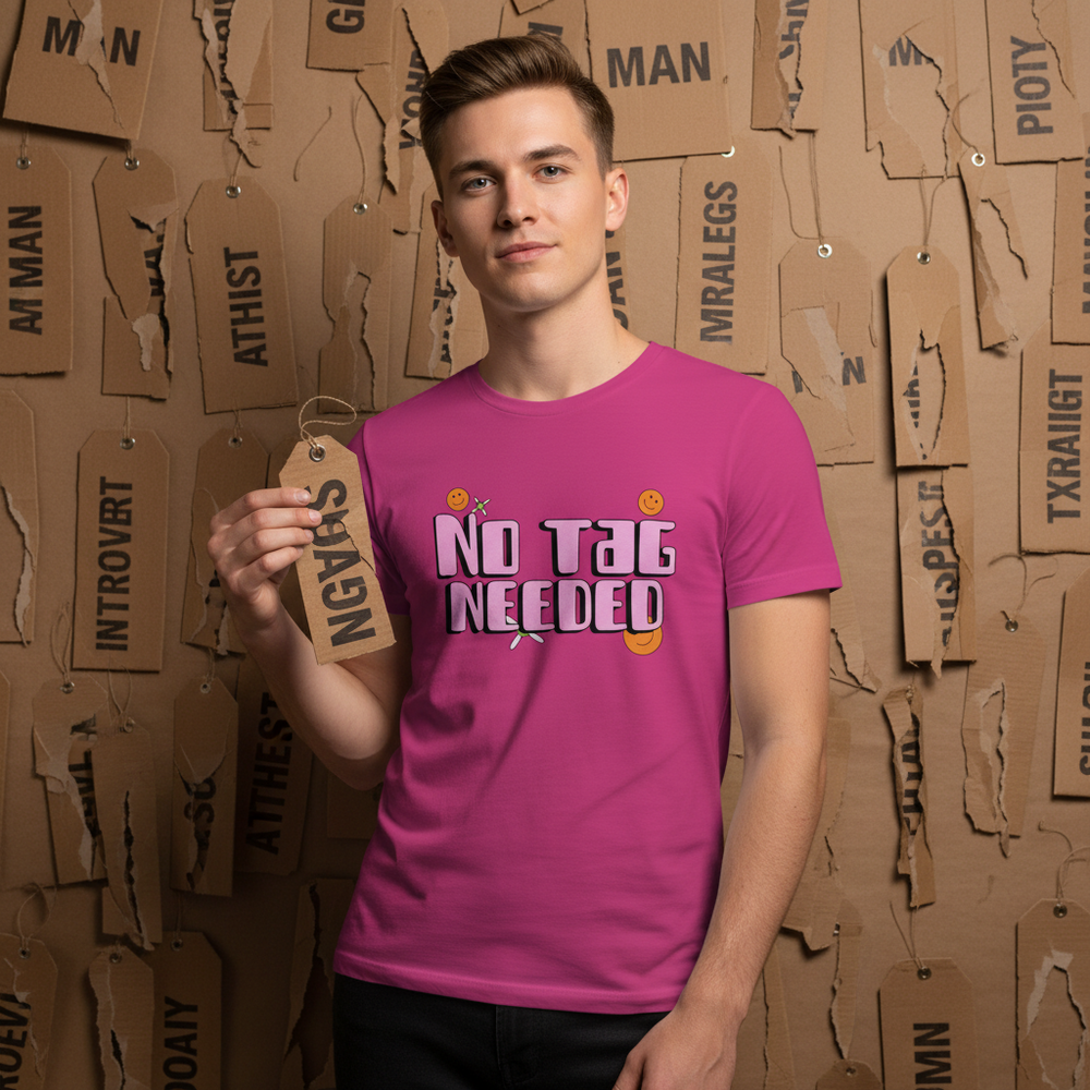 Person wearing a bright pink T-shirt reading “NO TAG NEEDED,” holding a paper tag