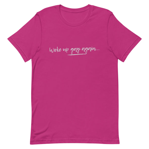 Unisex berry pink tee with short sleeves, “Woke up gay again…” in white script and brushstroke—queer pride and campy flair.