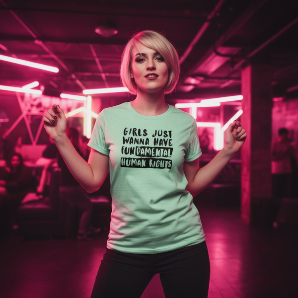 Girls Just Wanna Have Fundamental Human Rights T-shirt worn by a femme with short blonde hair in a neon-lit queer club scene.