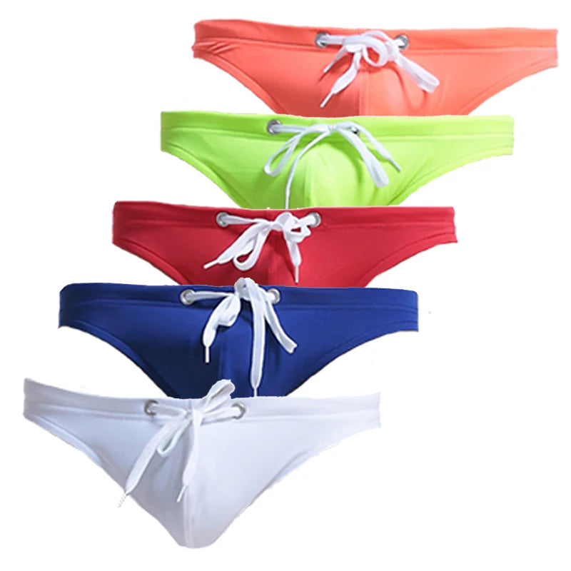 Five front-facing swim briefs in coral, lime, red, navy, and white with white drawstrings