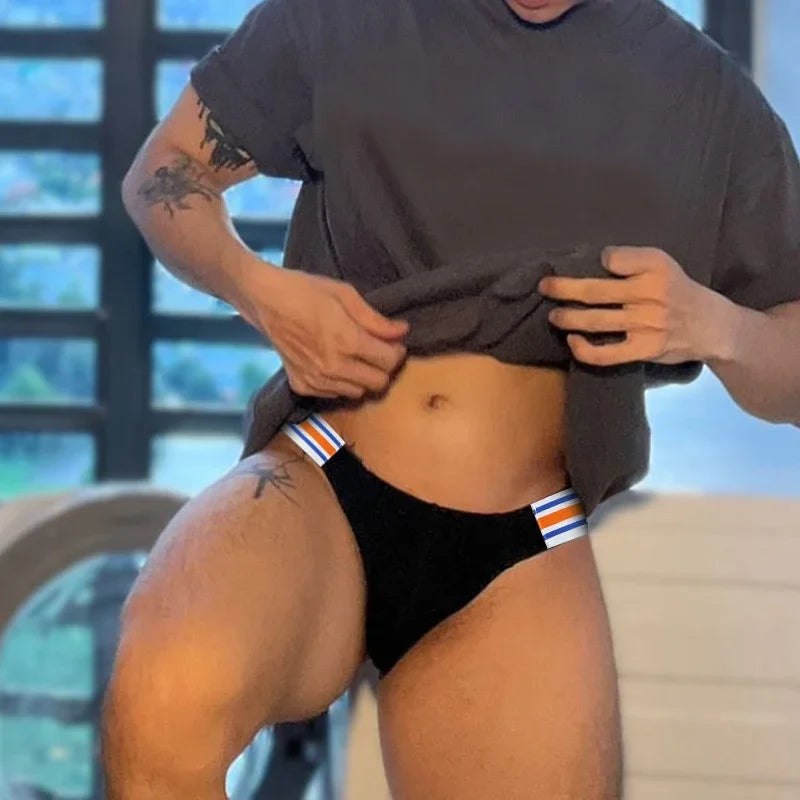 Front view of a model lifting a shirt to show black briefs with blue, white, and orange side stripes