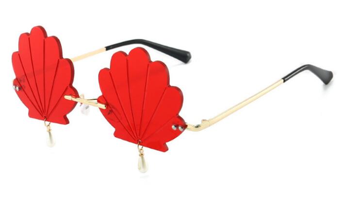 Rimless sunglasses with red scalloped shell-shaped lenses and dangling pearl-like charms