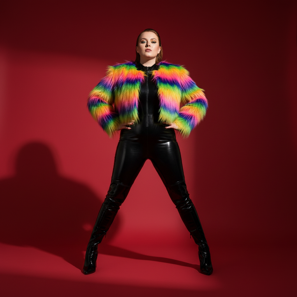 Front-facing model in a cropped rainbow faux-fur coat over a black catsuit and tall boots